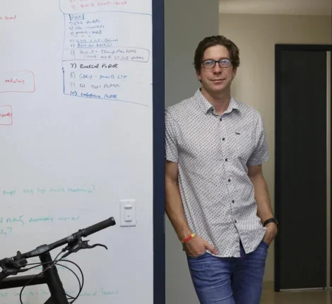 Gavin Rumbaugh leaning against white board