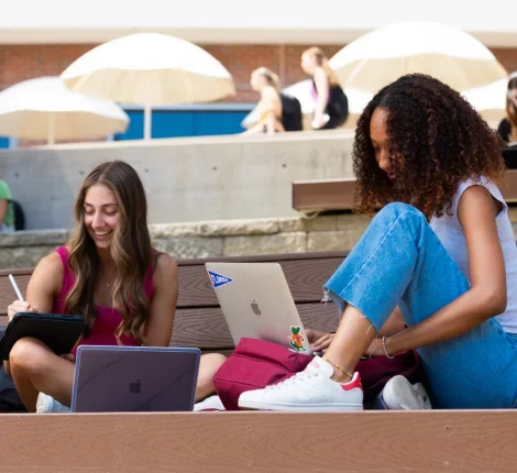 Two students sitting outside on a bench