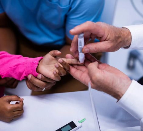 Child being tested for diabetes by finger stick performed by doctor.