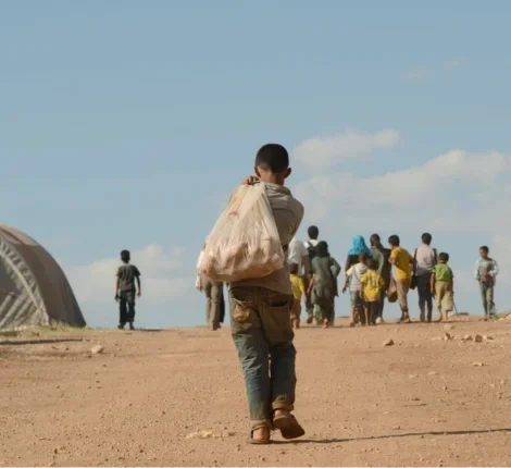 A child holding a bag over his shoulder walking.